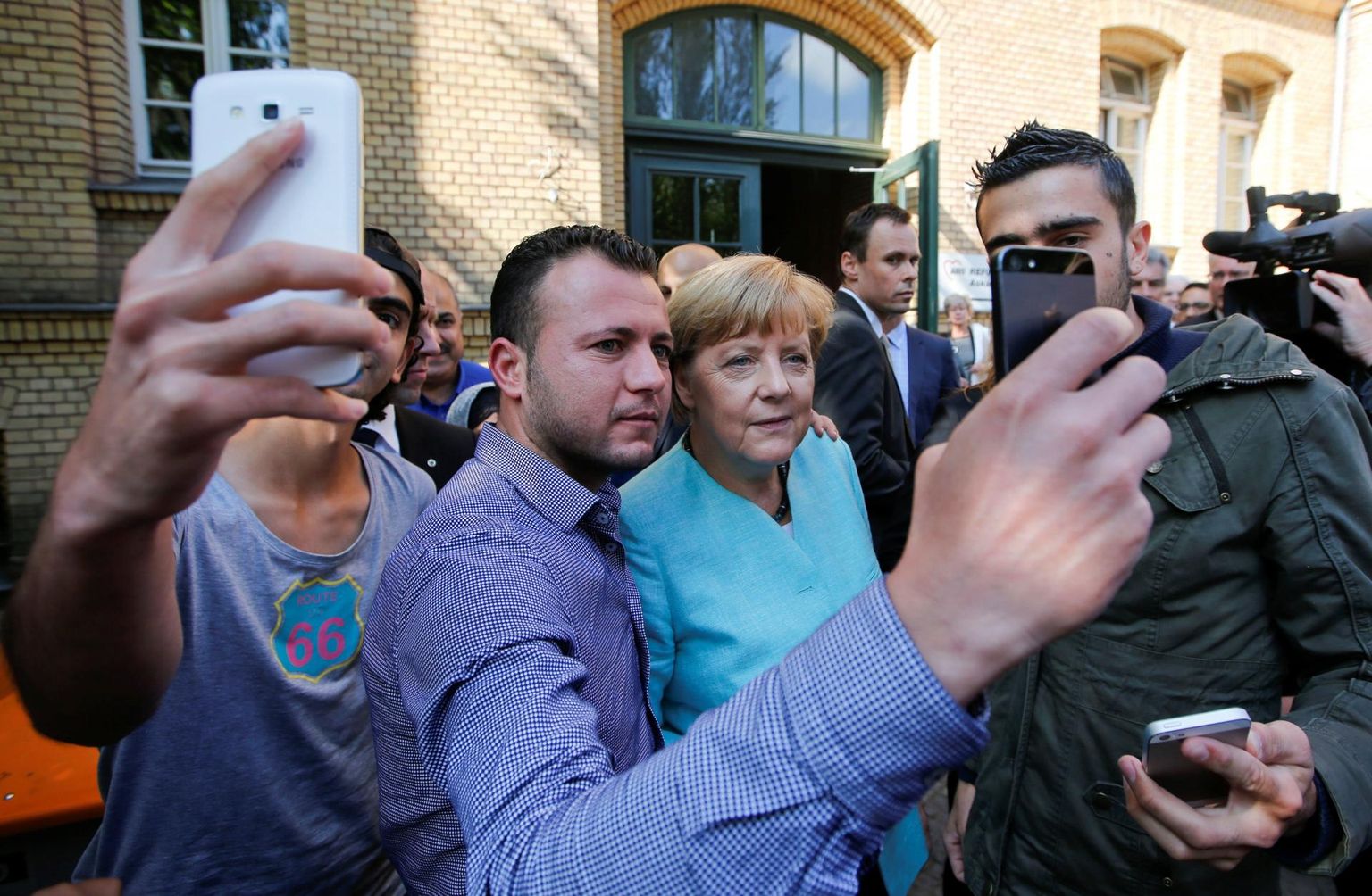 Saksamaa kantsler Angela Merkel poseerib selvefotoks koos Süüriast ja Iraagist pärit põgenikega Berliinis 2015. aasta sügisel. 