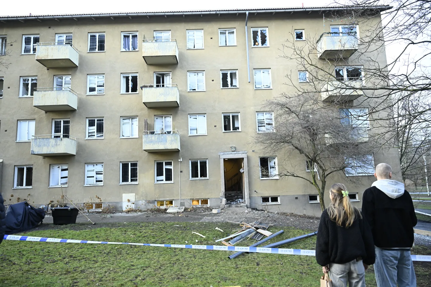 Люди рассматривают здание, поврежденное взрывом в районе Йоханнесхов на юге Стокгольма 18 января.