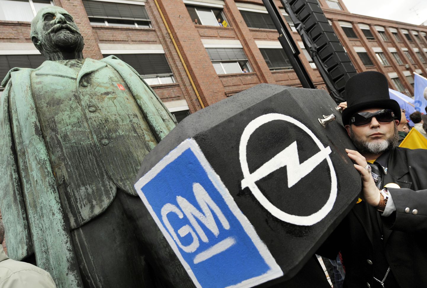 Opeli töötajad GMi ja Opeli logo kandva kirstuga.