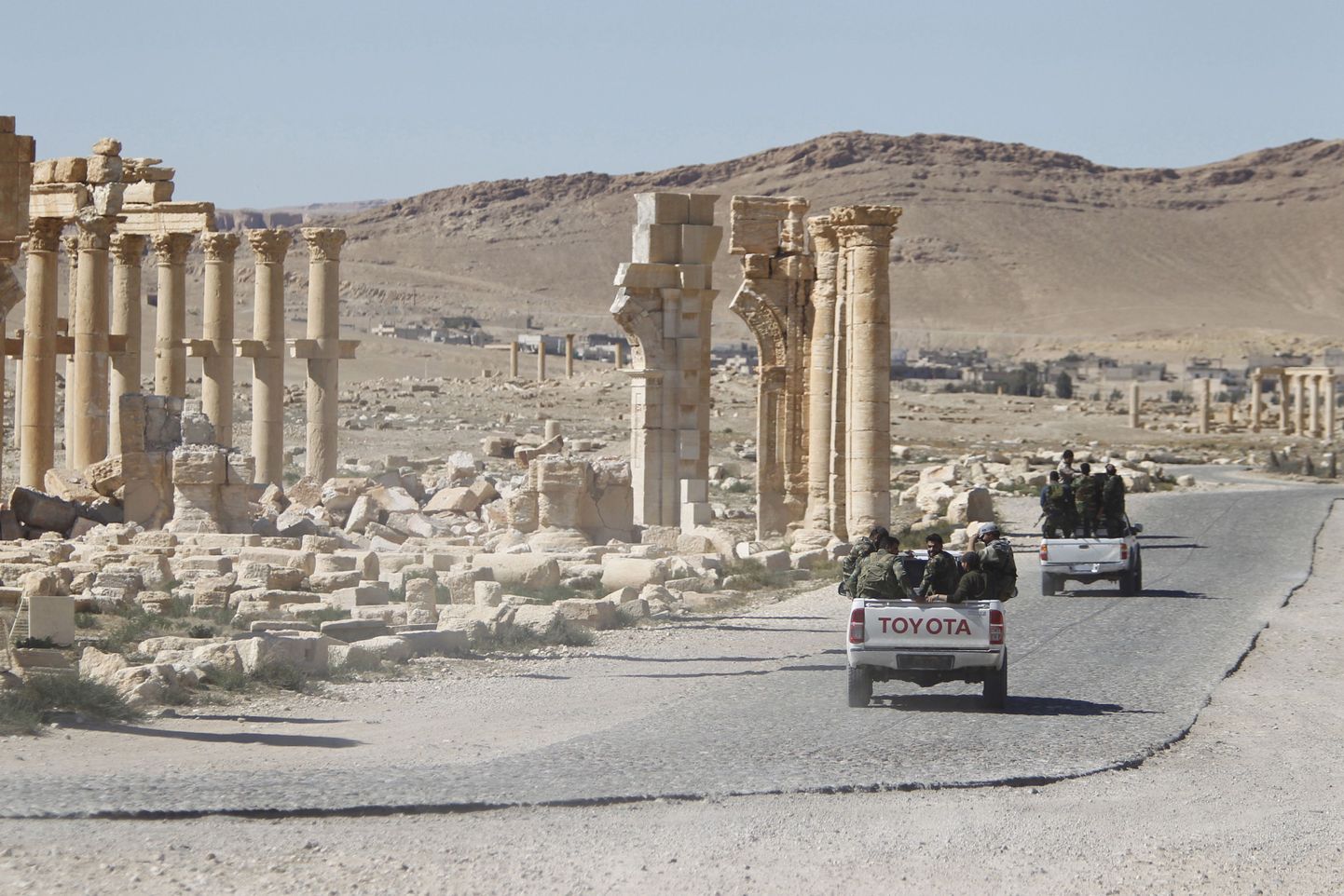 Süüria valitsusvägede sõdurid ja triumfikaare varemed Palmyras mullu aprillis tehtud fotol.