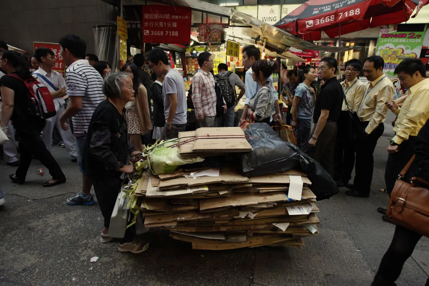 Eakas naine lükkamas käru vanapaberiga Hongkongis Mong Koki linnaosas. Paik on tuntud ostupiirkond, mida ilmestab segu vanematest ja uuematest kõrghoonetest, ning see on üldse maailma kõige tihedamini asustatud piirkond, kus elab 130 000 inimest ruutkilomeetri kohta.