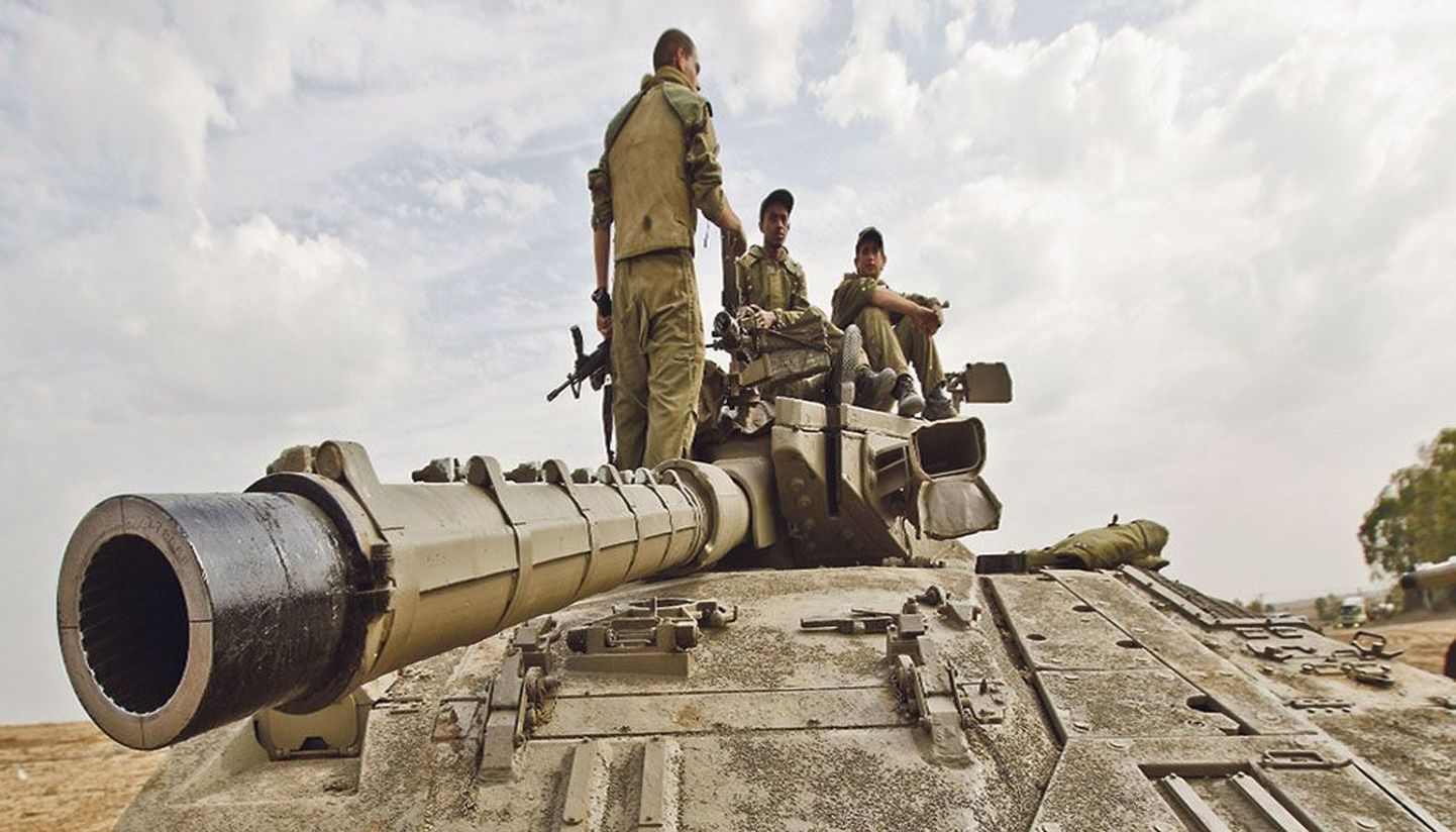 На танке, расположившемся у границы Газы, сидят военнослужащие Армии обороны Израиля, которые, как и тысячи других израильских солдат, ждут возможного приказа к вторжению.