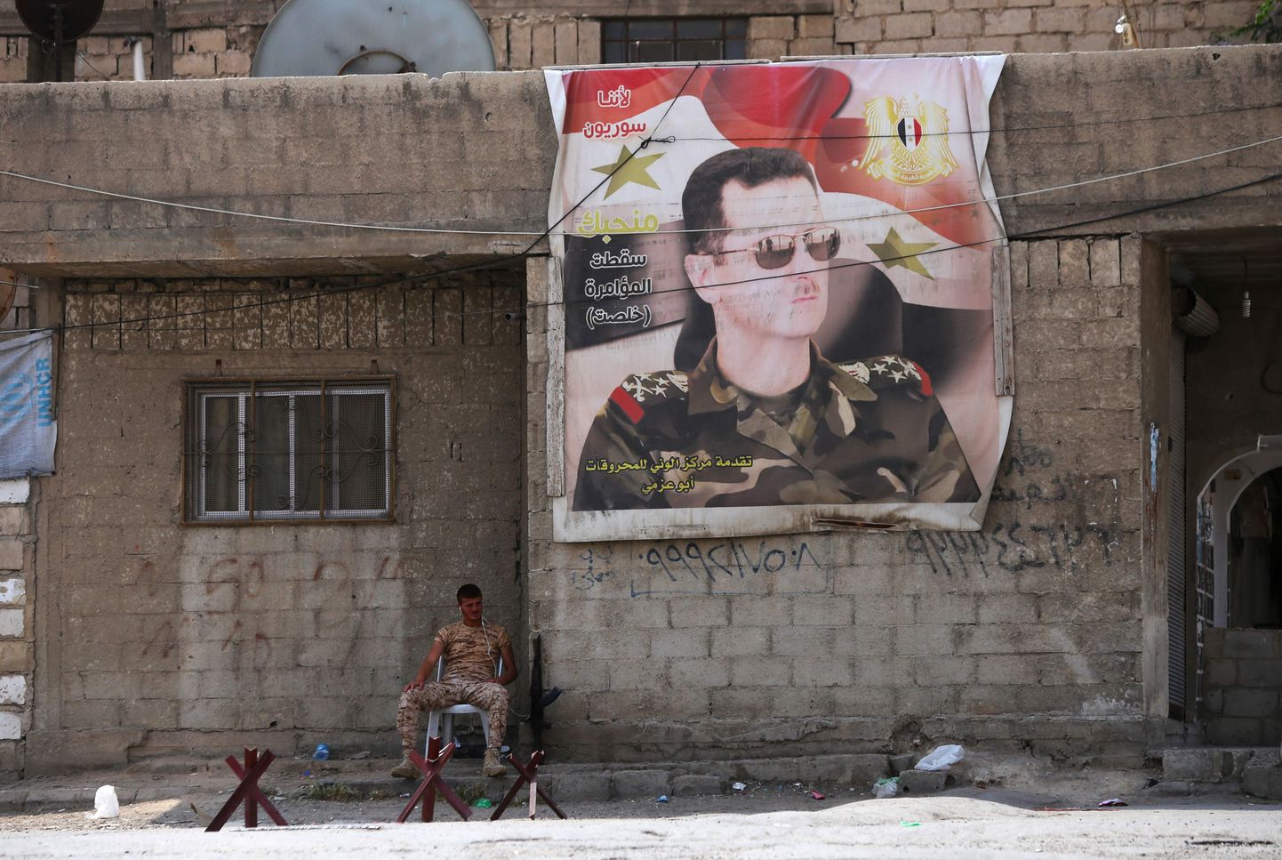 Süüria sõdur Wafideeni laagri ees. Seinal Bashar al-Assadi portree.