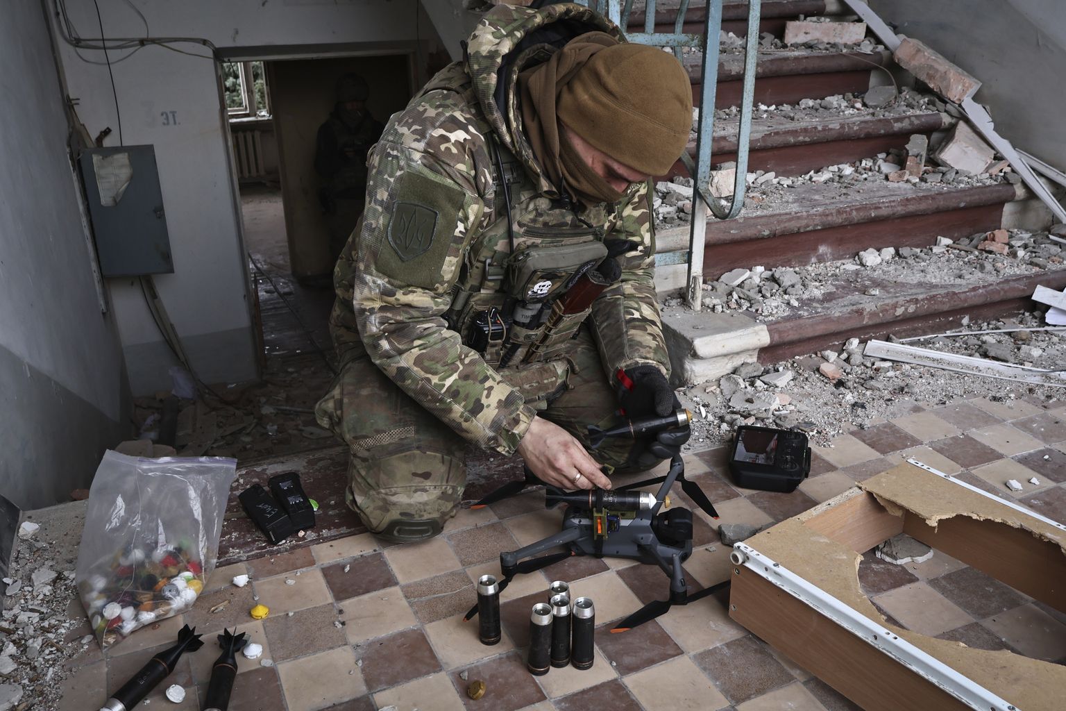 Ukraiņu karavīrs piestiprina dronam granātas smagāko kauju apvidū Bahmutā 2023. gada 15. martā