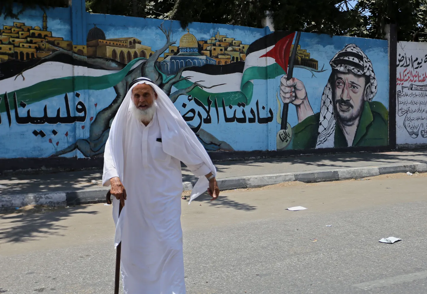 Mees jalutamas mööda kunagise Palestiina juhi Yasser Arafati seinmaalingust.