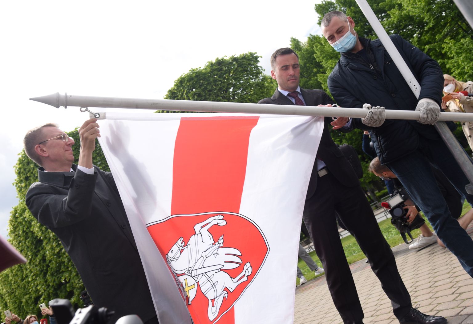 Ārlietu ministrs Edgars Rinkēvičs (no kreisās) un Rīgas domes priekšsēdētājs Mārtiņš Staķis Brīvības bulvāra un Elizabetes ielas krustojumā, kur izvietoti Pasaules hokeja čempionāta dalībvalstu karogi, aizstāj Baltkrievijas oficiālo karogu ar Baltkrievijas vēsturisko sarkanbalto karogu, paužot atbalstu Lukašenko režīma opozicionāriem un represētajiem.