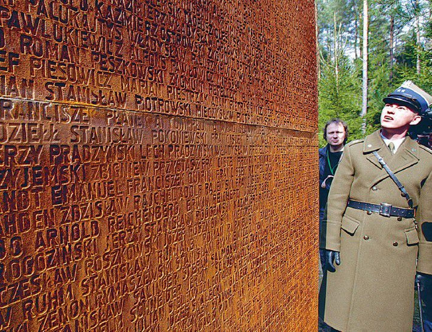 Польский солдат в лесу Катыни рассматривает мемориал, установленный на месте массового убийства его соотечественников, на стене которого высечены имена жертв кровавой бойни.