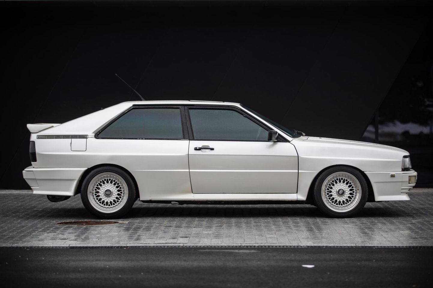 Mõneti üllatuslikult oli 1980.aastal esitletud Audi Quattro disaineriks inglane Martin Smith. Laiemast rööpmest tingitud rattakoopalaiendid andsid autole agressiivse ilme, millele sekundeerisid ühes tükis esispoiler ning auto pära maha vajutav antitiib.